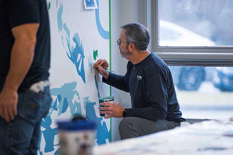 TVA employee working on mural.