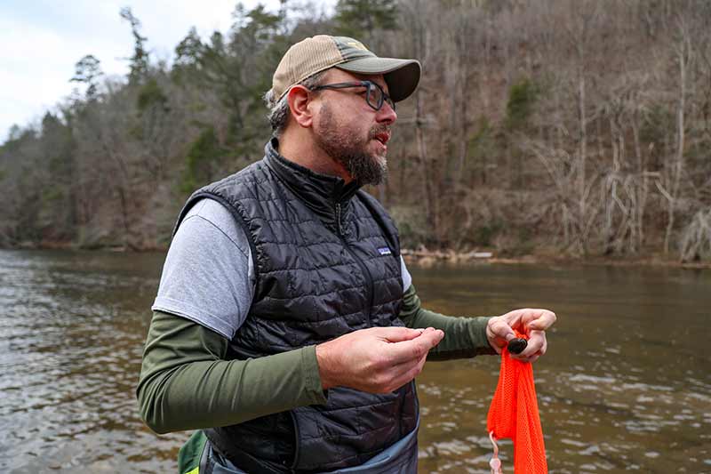 Biologist standing in river with mussels in hand