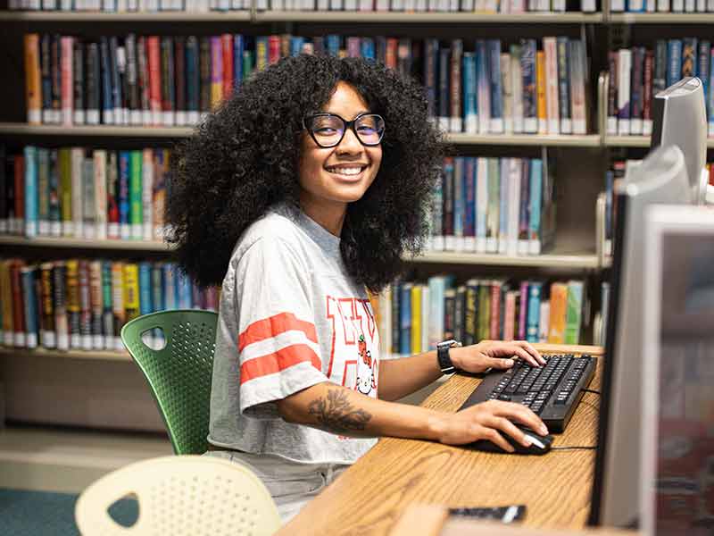 Teen at computer keyboard in library