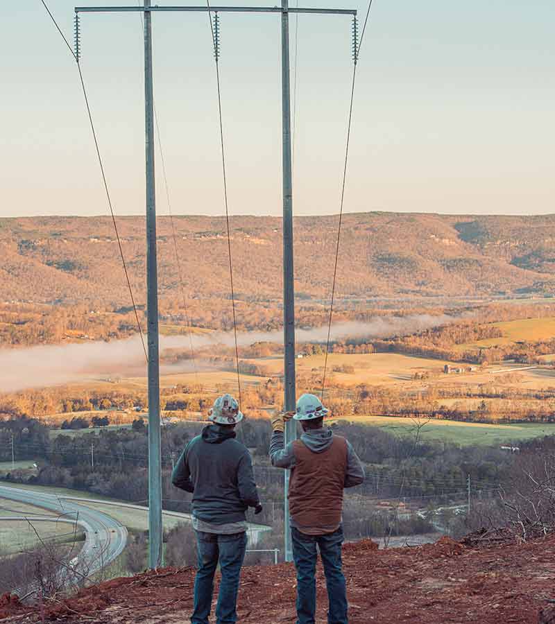 Lineworkers standing near transmission lines.