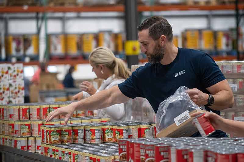 Man in TVA shirt packing canned food for distribution