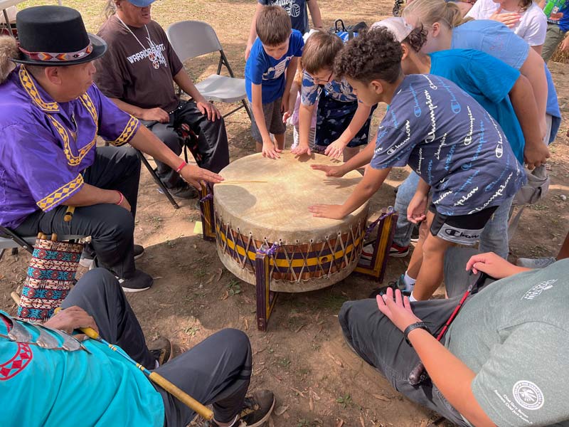 Five students at the Oka Kapassa Festival bang on a Native American-style drum