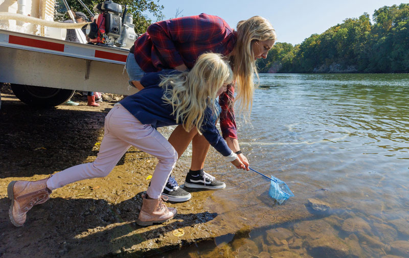 A mother and daughter release a young sturgeon into the French Broad River at the Sturgeonfest event in east Tennessee