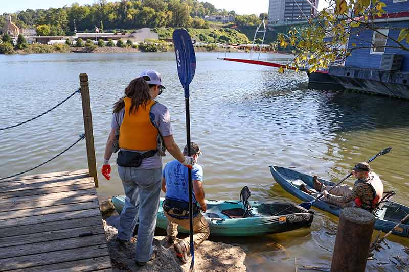 Volunteers in kayaks at river bank