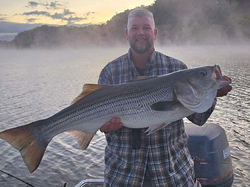 TVA Fun photo of fisherman holding up large catch on misty lake