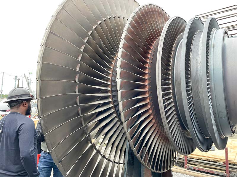 A TVA team member stands next to a turbine component at Ackerman Combined Cycle Plant