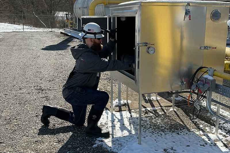 Worker kneeling while checking equipment at Brownsville Combustion Turbine Plant