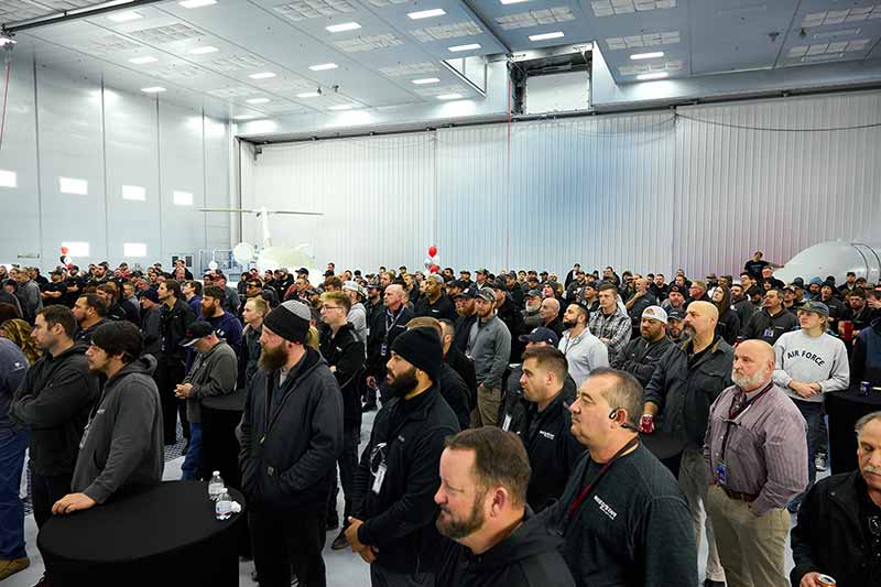 Group of West Star Aviation employees stand at announcement of expanded operations.
