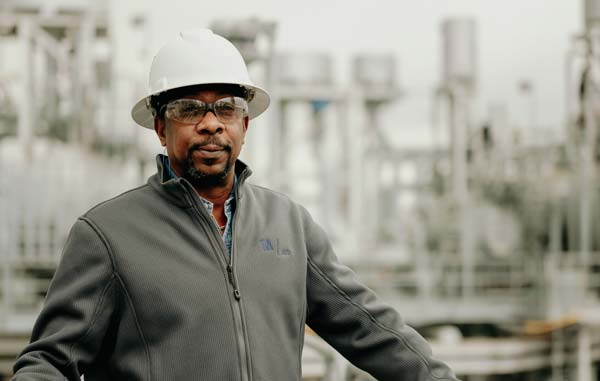 Man wearing a safety helmet and safety glasses in an industrial background