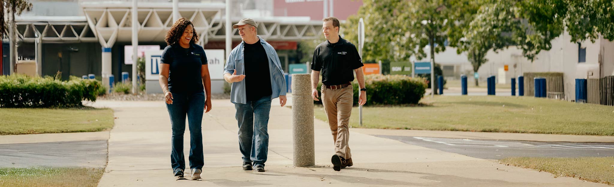 Three people walking together on a sidewalk near a building.