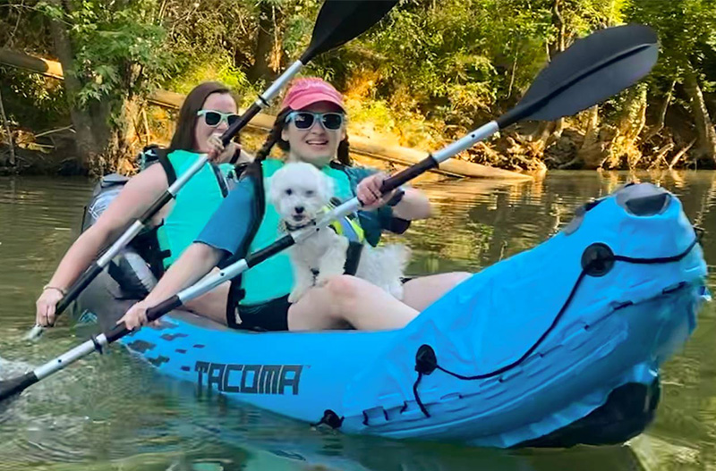 Two women kayaking with a dog