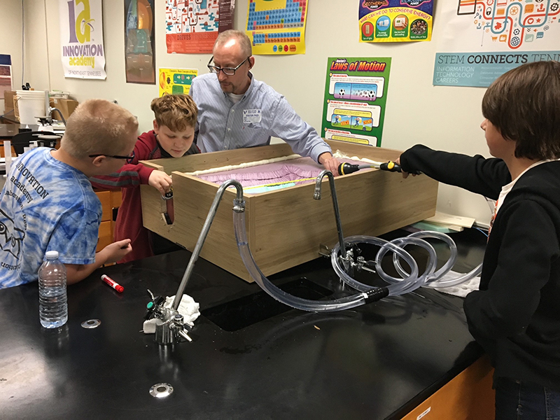 Chris Saucier shows dam model to students