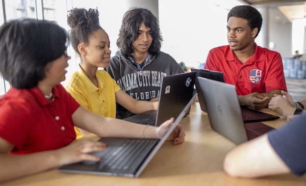 Students sitting at a table with a computer