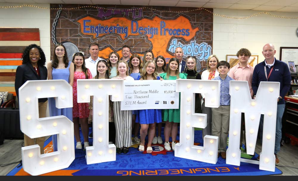 Group photo with a STEM sign and a large check.